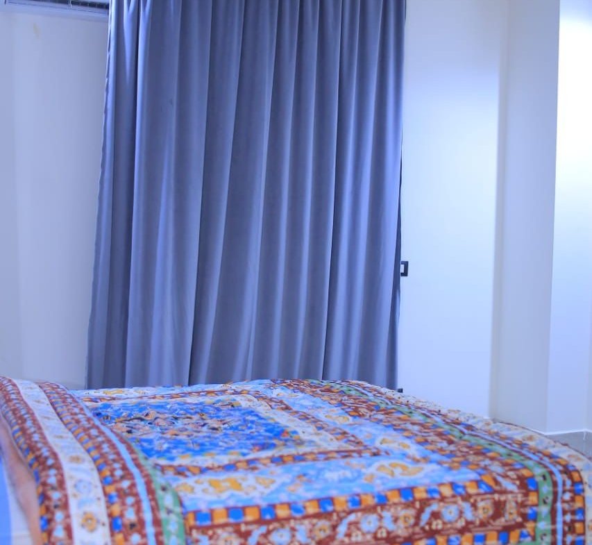 Bed with a colourful patterned cover and blue curtains - apartment in El Yasmeen 1, New Cairo