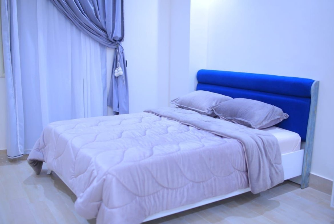 Double bed with a blue headboard and lilac bedding - apartment in El Yasmeen 1, New Cairo
