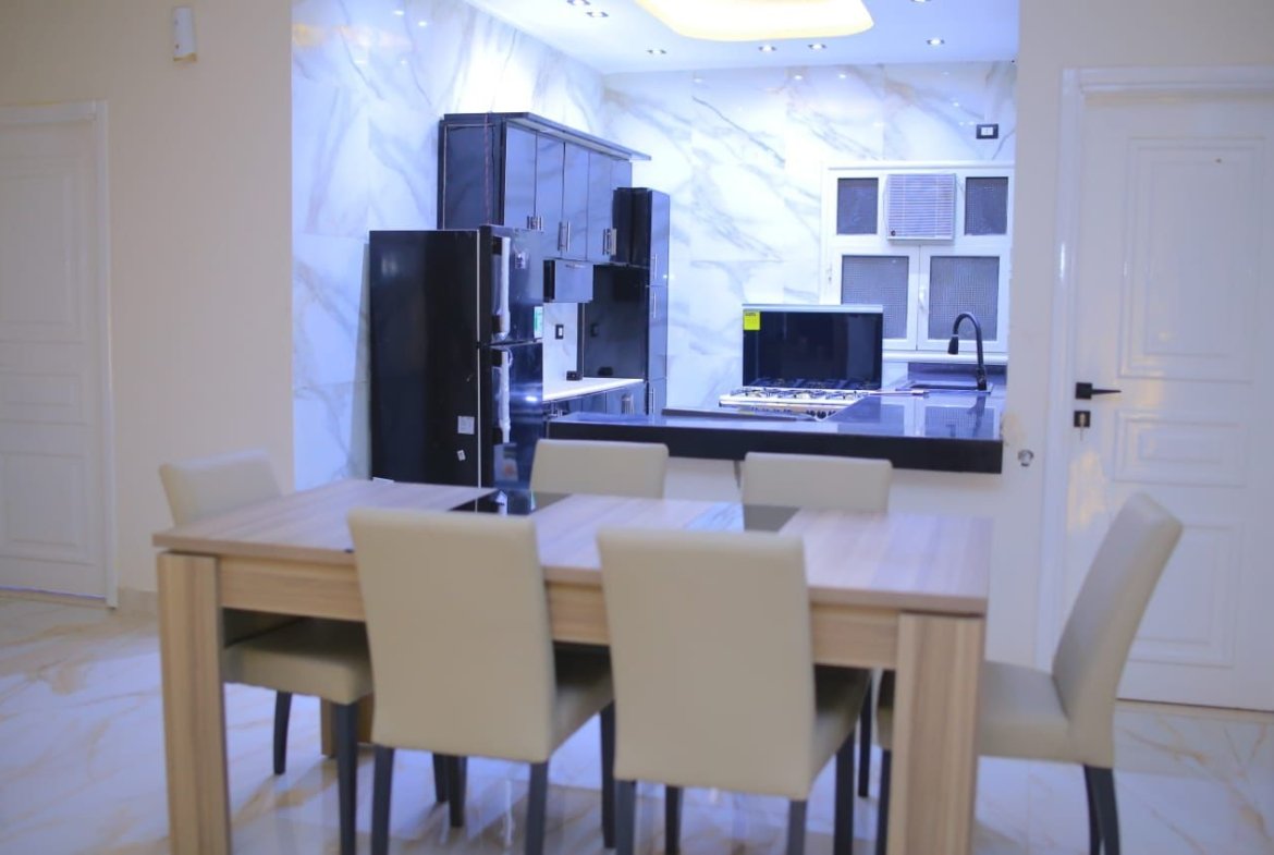 Dining area with beige chairs facing a marble kitchen wall - apartment in El Yasmeen 1, New Cairo