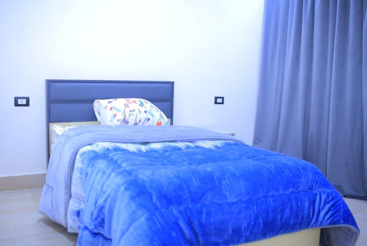 Single bed with a bright blue blanket and a floral pillow - apartment in El Yasmeen 1, New Cairo