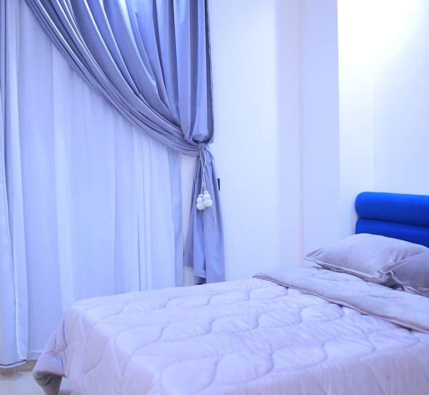 Bed with lilac bedding beside a draped curtain - apartment in El Yasmeen 1, New Cairo