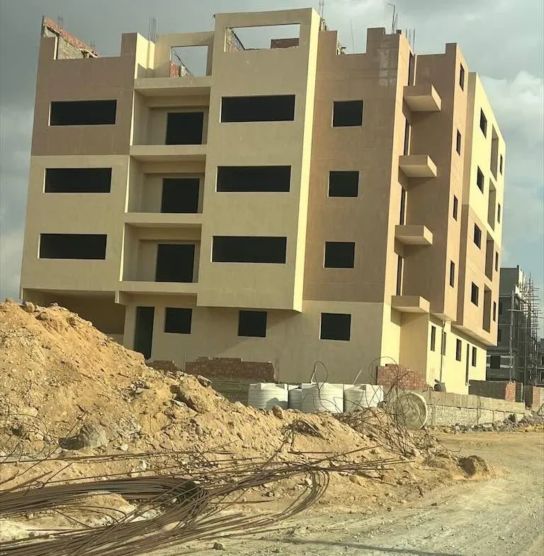 عمارة بيج تحت الإنشاء وأمامها تلة رمل - شقة في بيت الوطن، التجمع الخامس