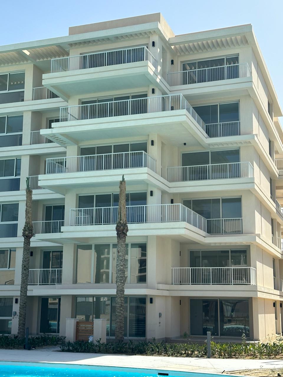 واجهة مبنى سكني أبيض ببلكونات زجاجية - شاليه في مراسي مارينا فيو