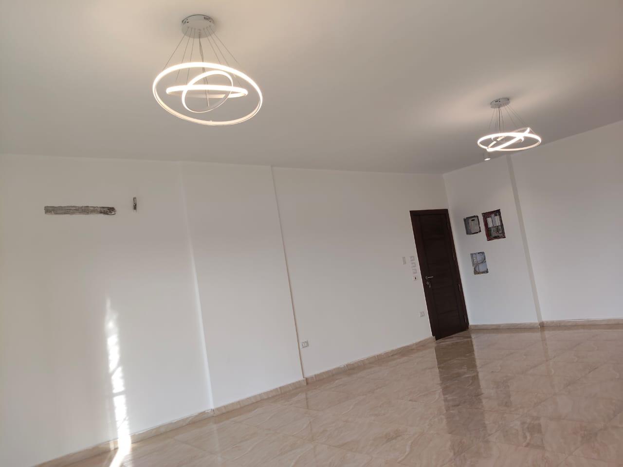 property-image-69ebfd2024180 Bright room with two ring ceiling lights and a polished floor - apartment in Capital Gardens, New Cairo