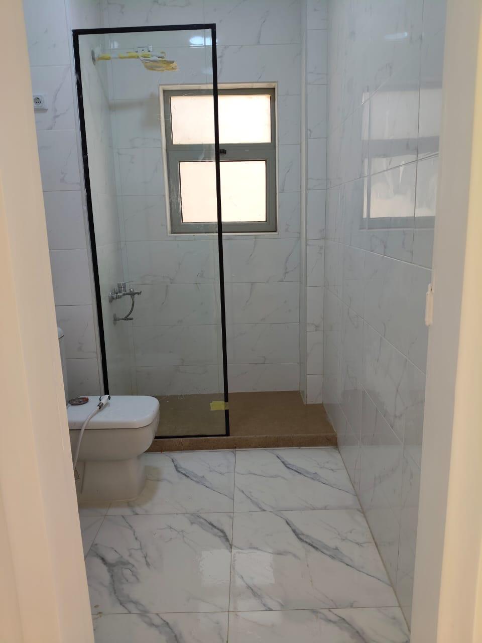 property-image-69ebfd24c21ed Bathroom with a black-framed glass shower and white marble tiles - apartment in Capital Gardens, New Cairo
