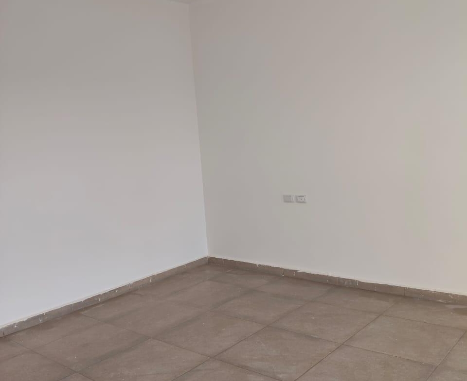 Empty room with a pendant light and a grey tiled floor - apartment in Capital Gardens, New Cairo