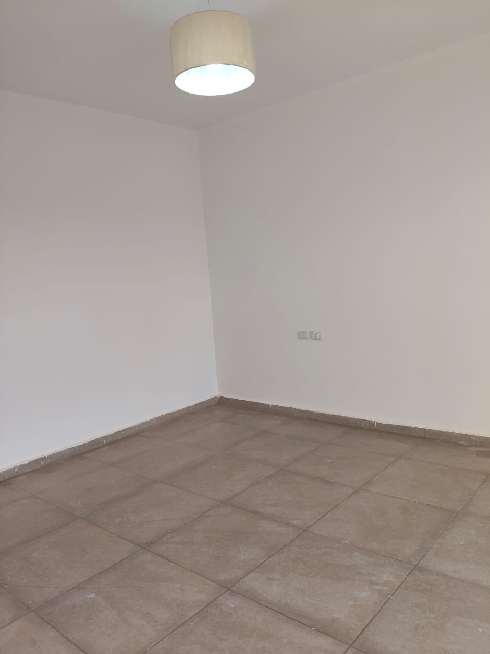 property-image-69ebfd25d19d0 Empty room with a pendant light and a grey tiled floor - apartment in Capital Gardens, New Cairo