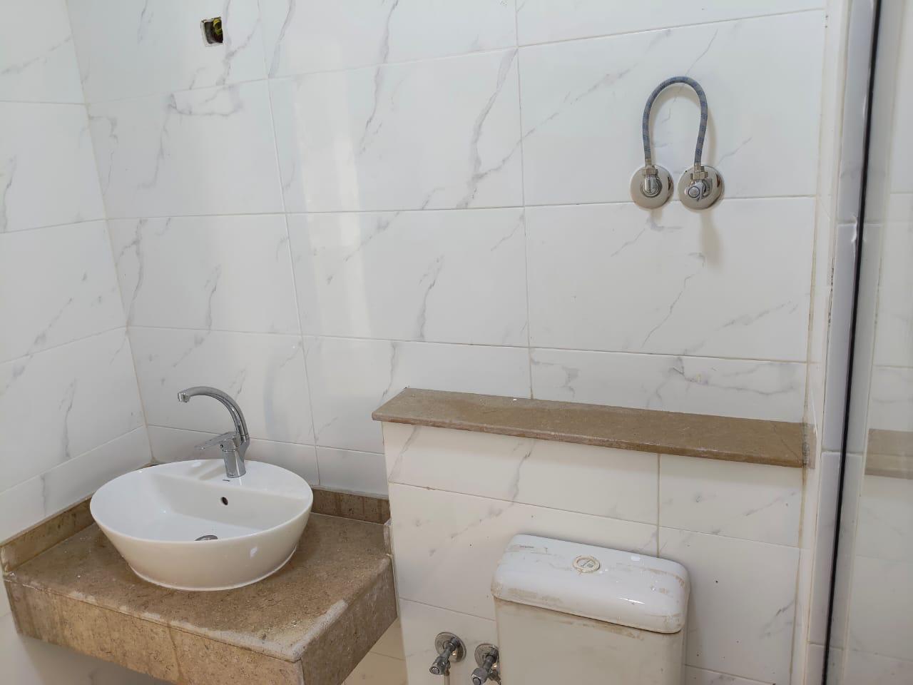 property-image-69ebfd2907dba Bathroom with a vessel basin on a marble shelf and white wall tiles - apartment in Capital Gardens, New Cairo