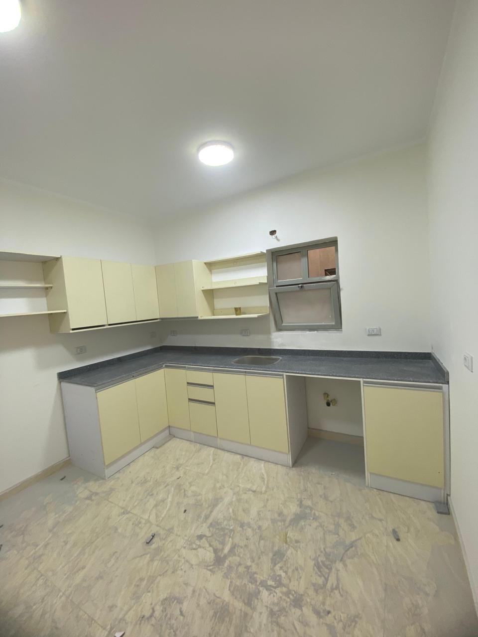 property-image-69ebfd2b3539f Corner kitchen with a dark counter and a marbled floor - apartment in Capital Gardens, New Cairo