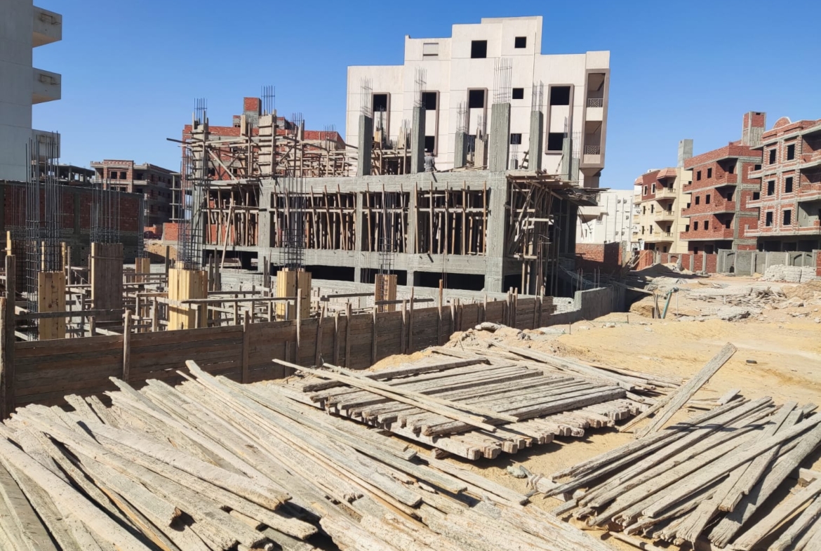 Panoramic view of a construction plot with stacked timber and new buildings - apartment in Beit El Watan, New Cairo