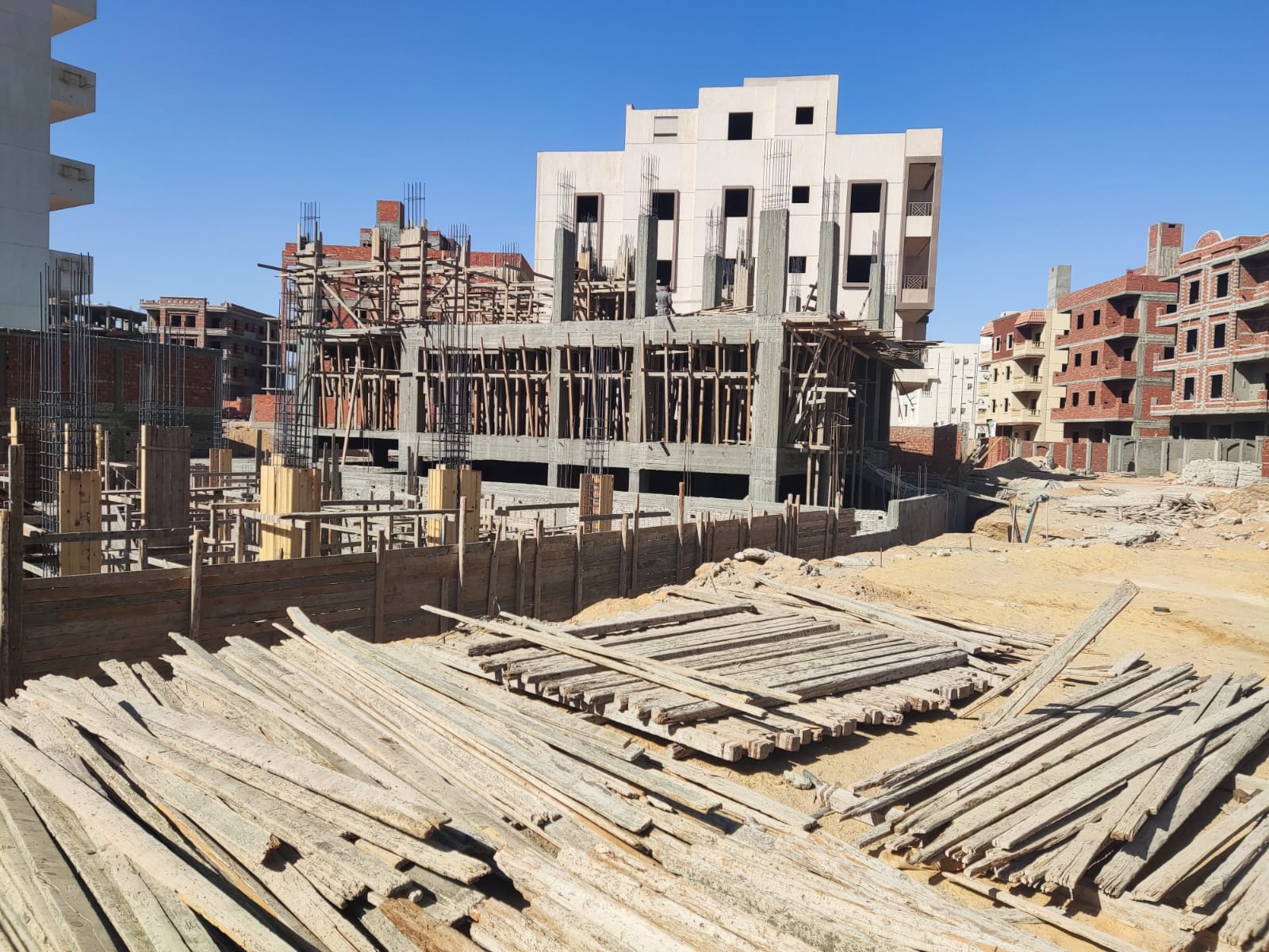 Panoramic view of a construction plot with stacked timber and new buildings - apartment in Beit El Watan, New Cairo