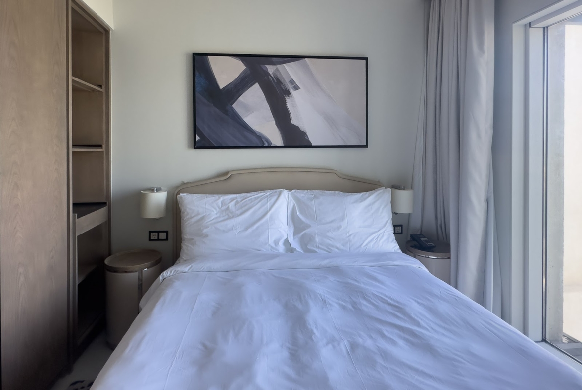 Double bed with padded headboard and abstract painting - hotel apartment in Marassi The Address Beach, North Coast
