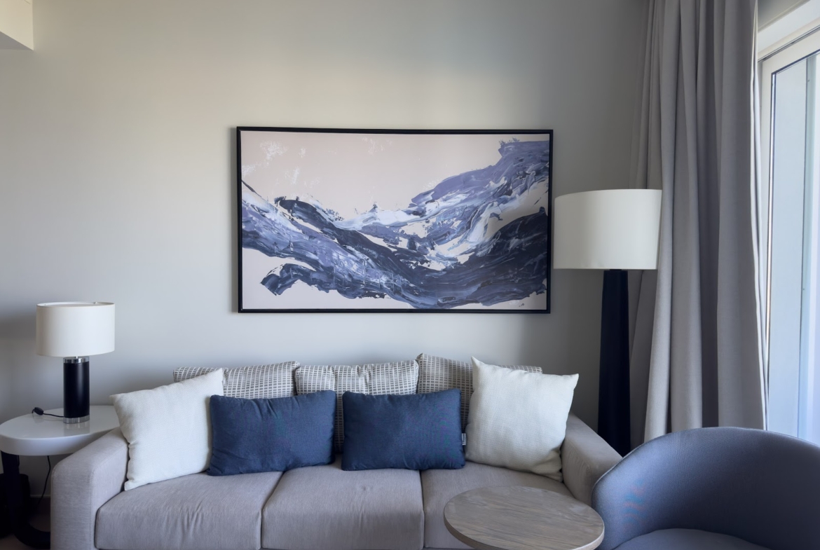Grey sofa with blue cushions below a mountain painting - hotel apartment in Marassi The Address Beach, North Coast