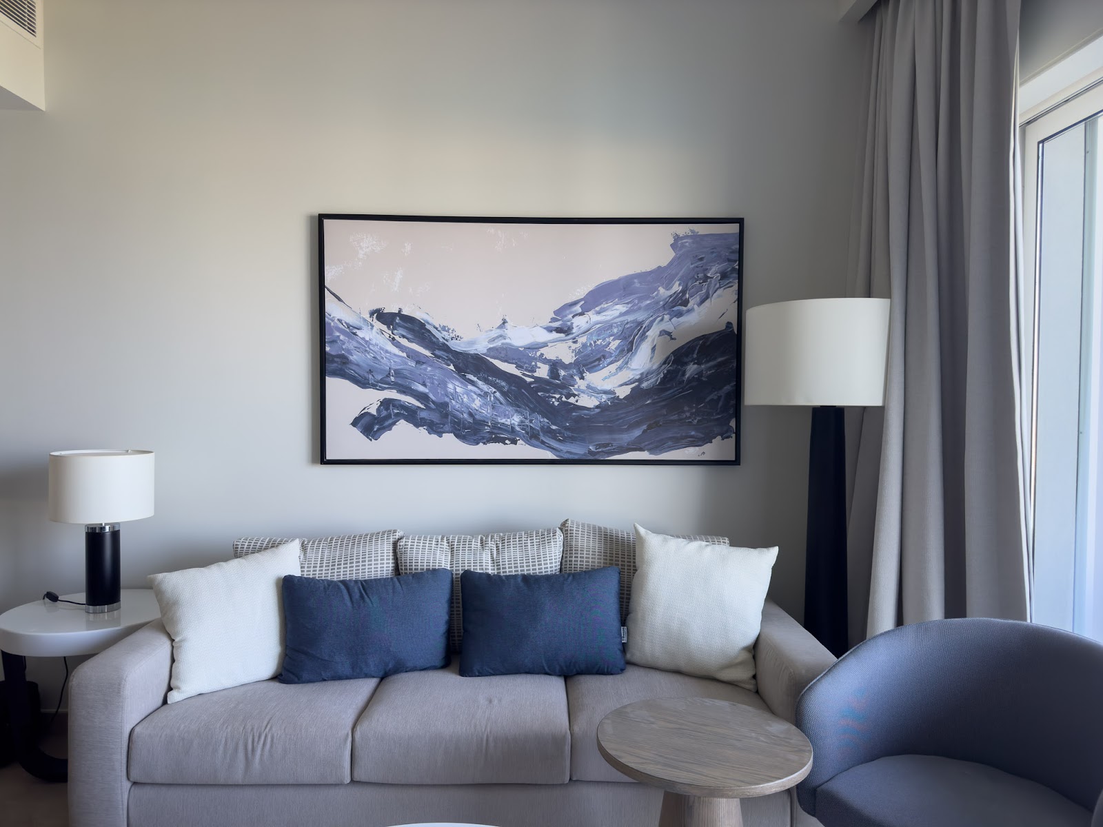 Grey sofa with blue cushions below a mountain painting - hotel apartment in Marassi The Address Beach, North Coast