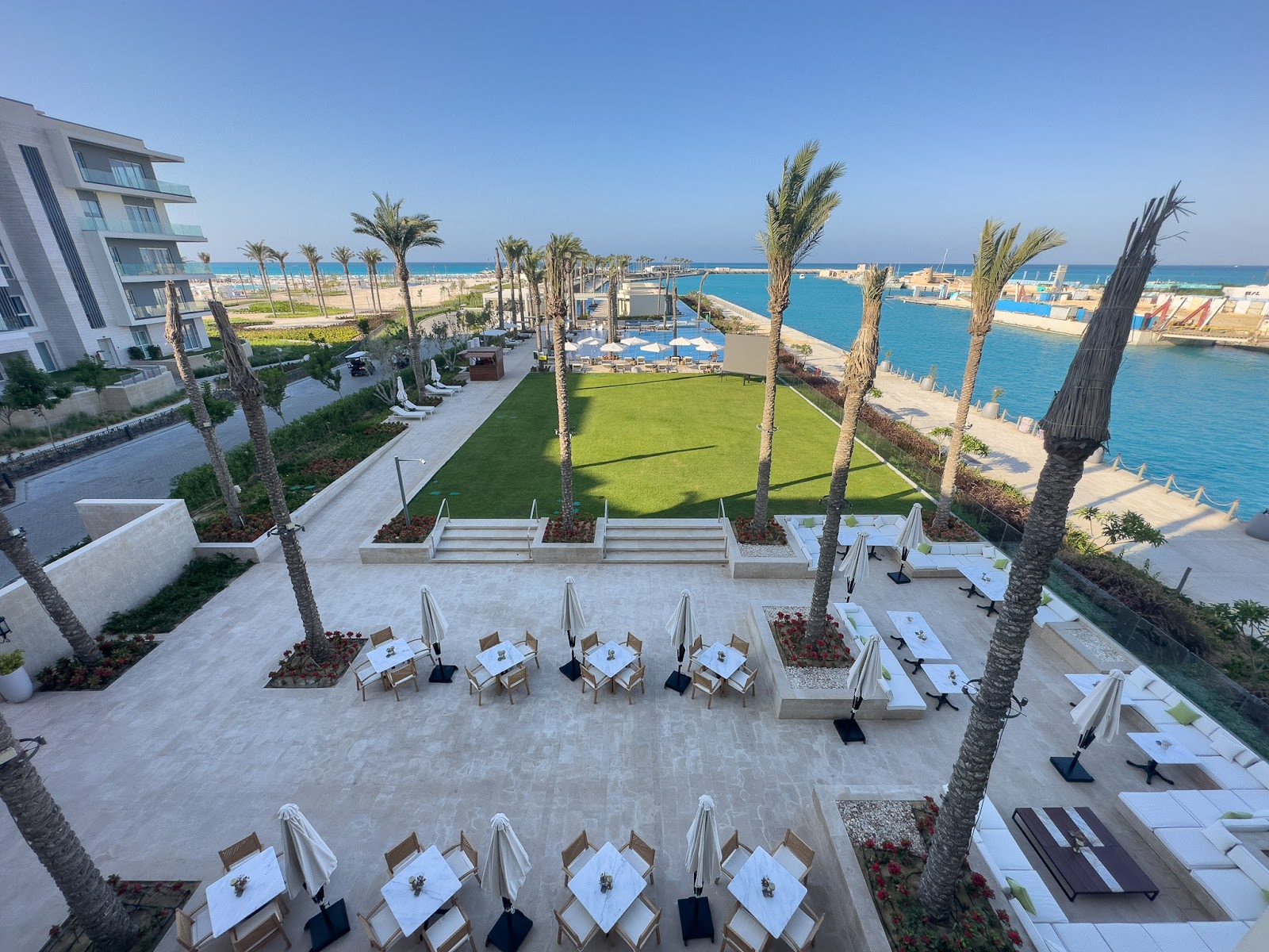 Terrace with sun loungers and umbrellas beside the marina - hotel apartment in Marassi The Address Beach, North Coast