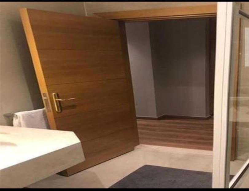 Wooden door opening to a bathroom basin and a hallway - penthouse in Lake View, New Cairo