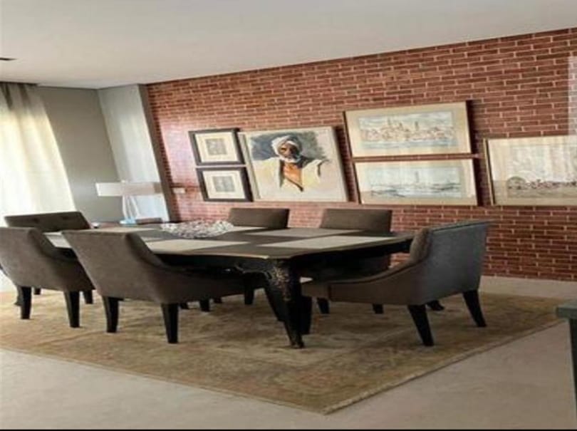 Dining table with grey chairs in front of a red brick wall - penthouse in Lake View, New Cairo