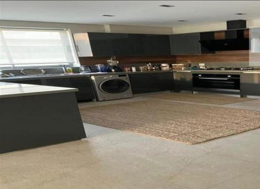 Open kitchen with dark cabinets, a washing machine and a woven rug - penthouse in Lake View, New Cairo