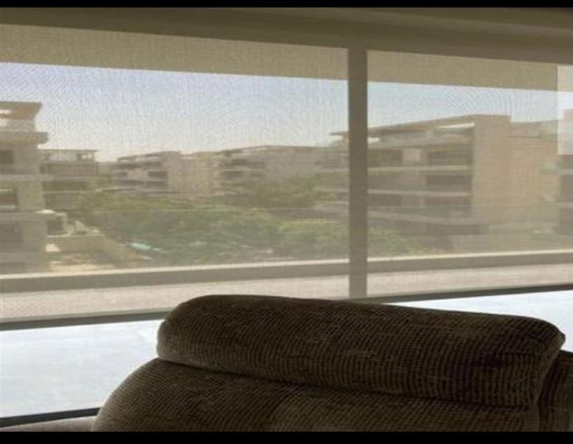 Sofa corner by a large window with a view of neighbouring buildings - penthouse in Lake View, New Cairo