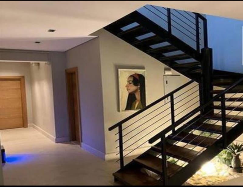 Staircase with black steps, a steel railing and a framed portrait - penthouse in Lake View, New Cairo