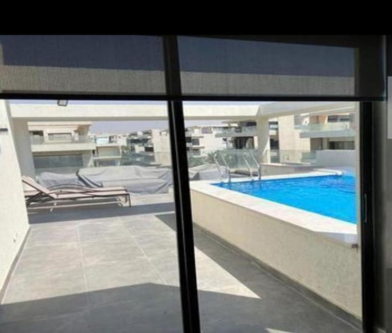 Pool terrace seen through a sliding glass door - penthouse in Lake View, New Cairo