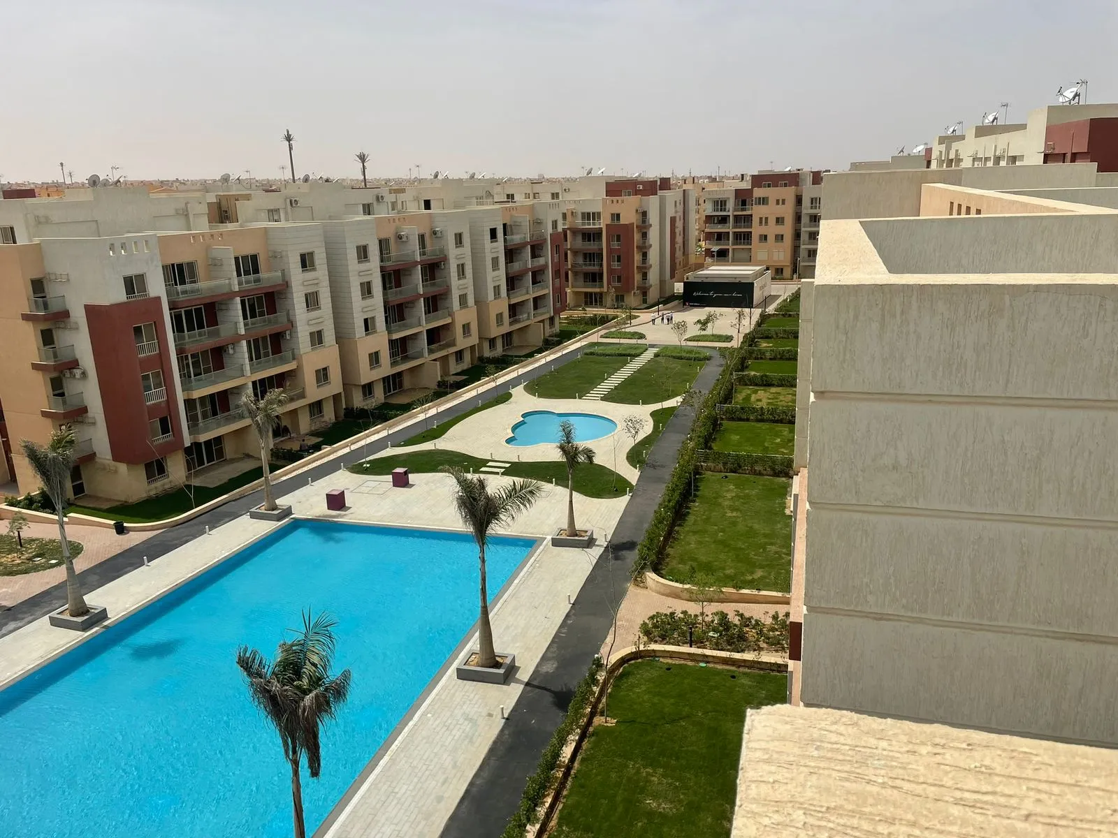 Long pool and lawns between apartment blocks seen from above - penthouse in Promenade, New Cairo