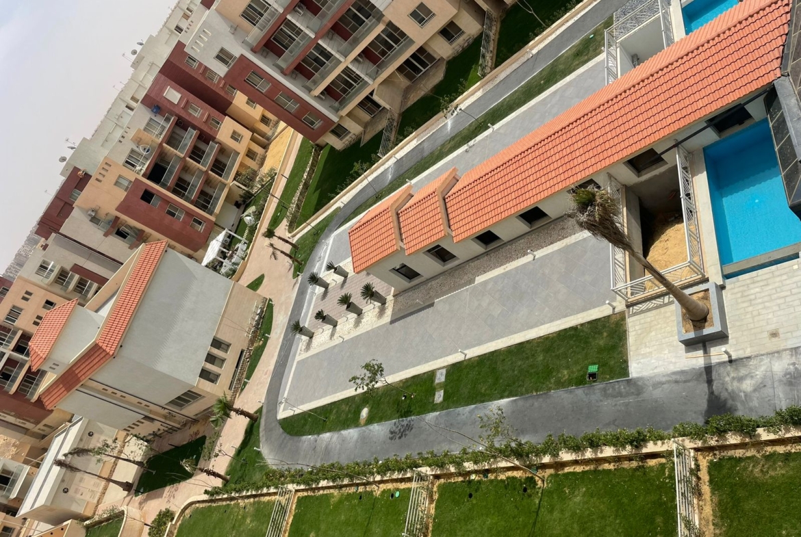 Top-down view of a terracotta roof strip, lawns and a pool corner - penthouse in Promenade, New Cairo