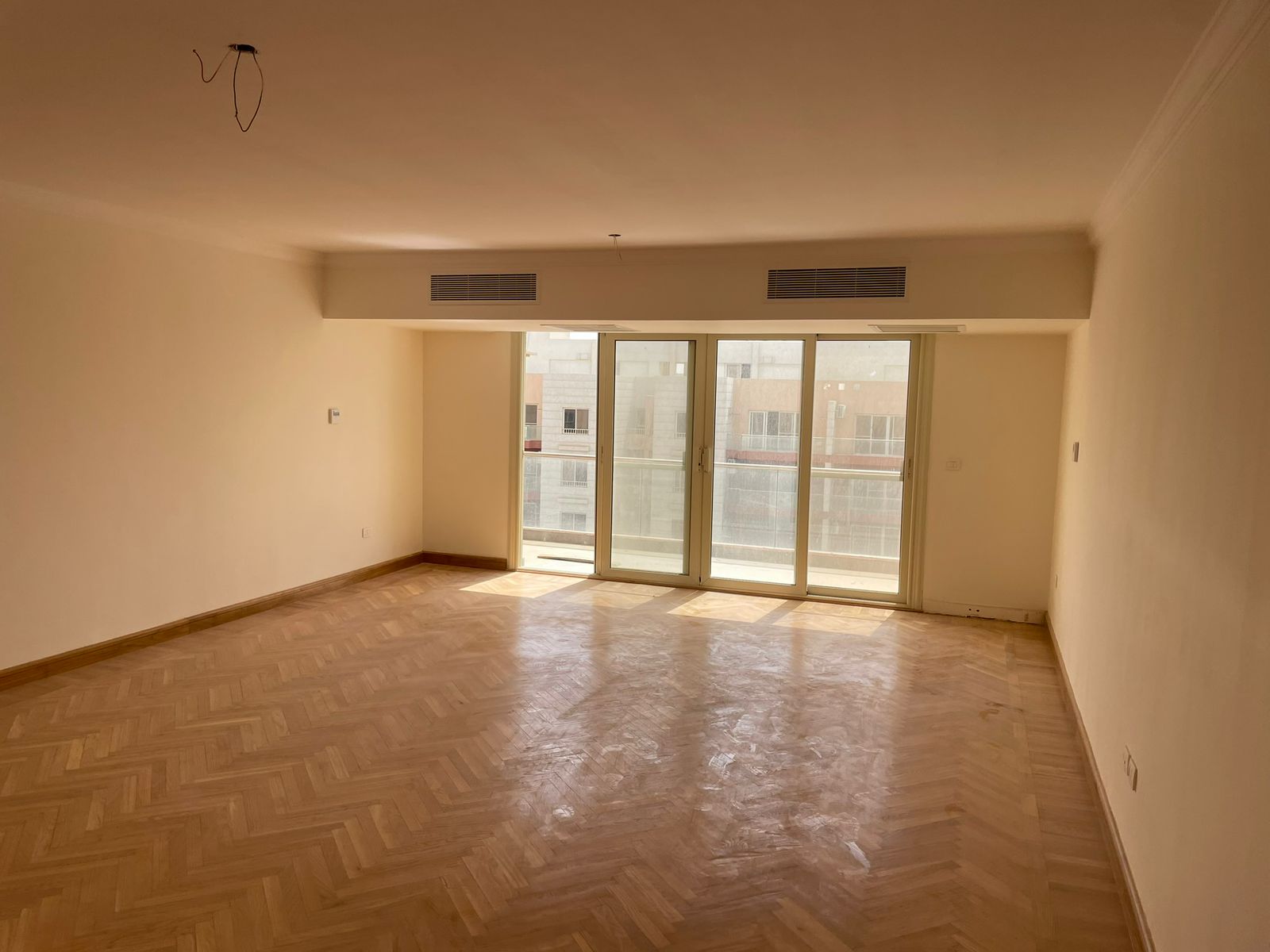 Empty living room with glass doors and a parquet floor - penthouse in Promenade, New Cairo