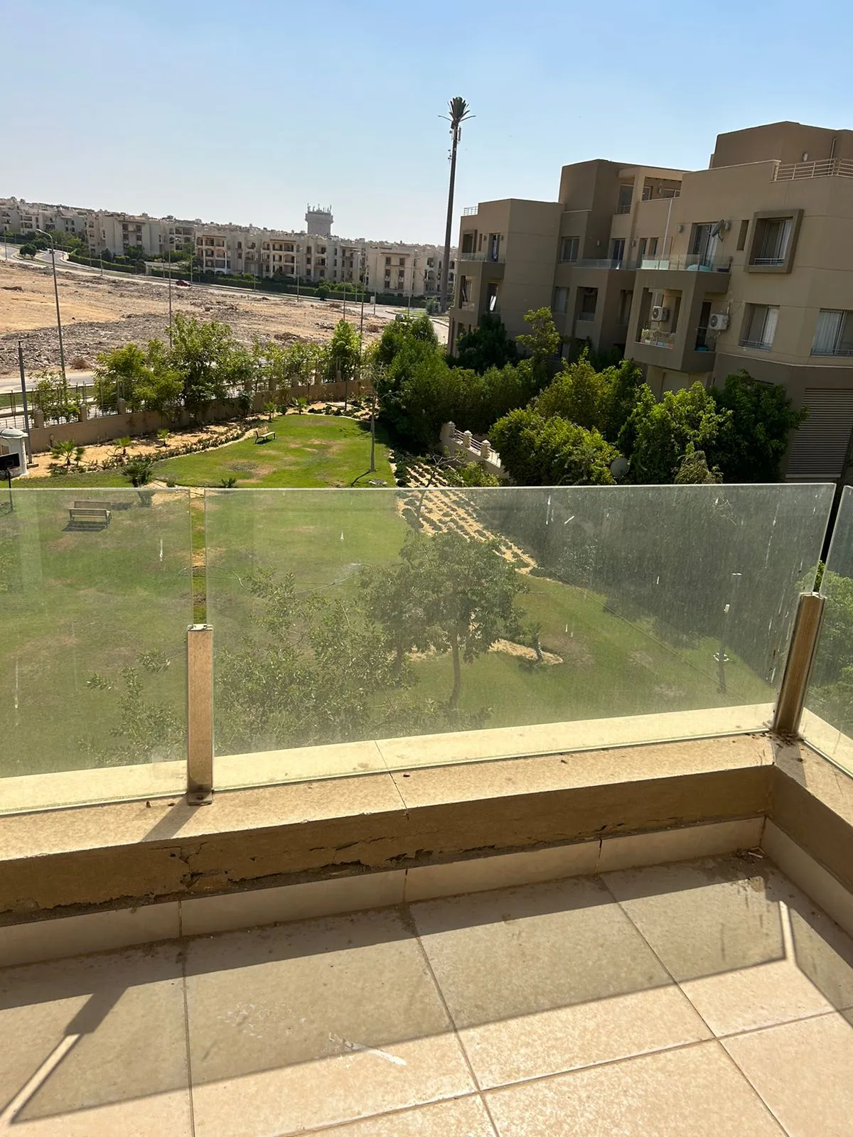 Glass-railed balcony looking at gardens and neighbouring buildings - duplex in Village Gate, New Cairo