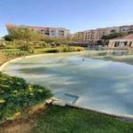 Lagoon curving past a lawn with a pavilion in the distance - apartment in Regents Park, New Cairo