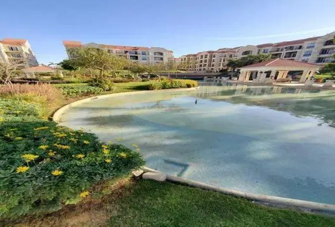 Lagoon curving past a lawn with a pavilion in the distance - apartment in Regents Park, New Cairo