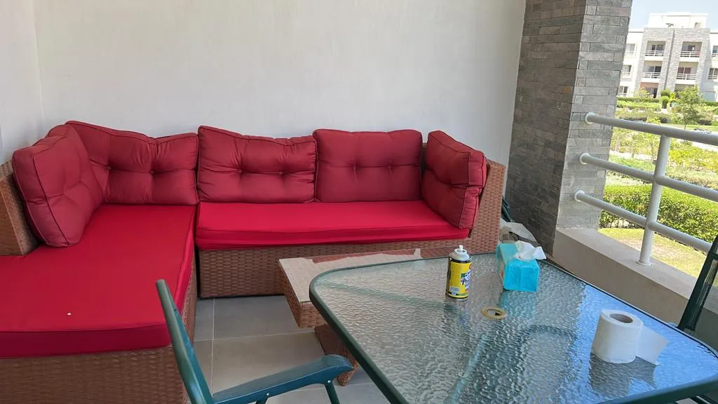 Balcony with red cushioned corner sofa and a glass table - chalet in Amwaj, North Coast