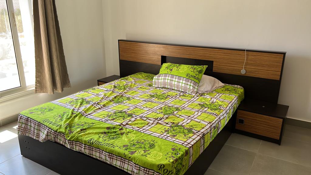 Double bed with green checkered cover and wooden headboard - chalet in Amwaj, North Coast