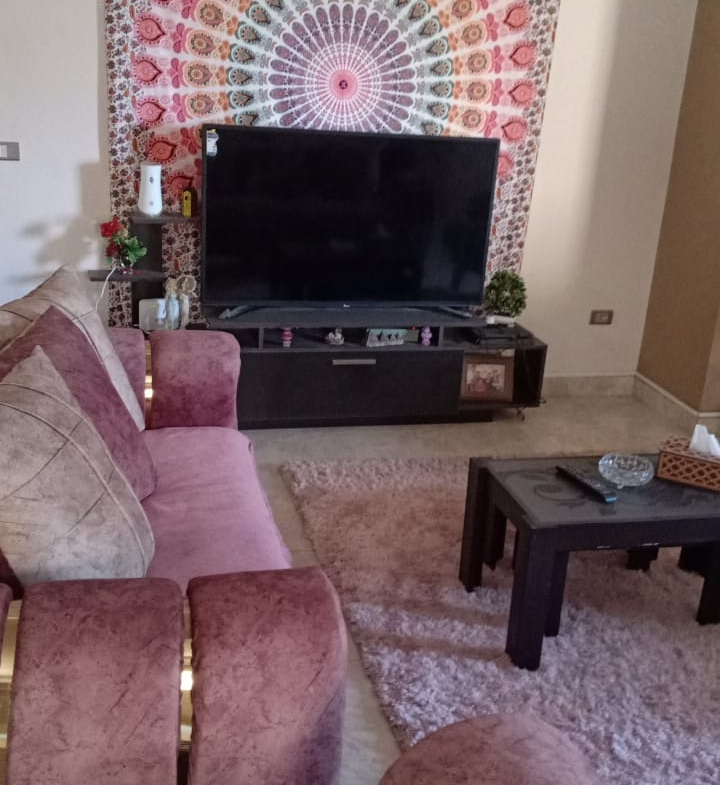 Pink sofas facing a TV with a mandala wall hanging - duplex in South of Academy, New Cairo