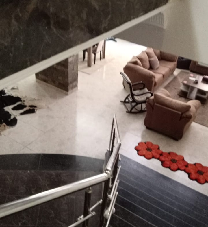 Stair railing overlooking a living area with red cushions - duplex in South of Academy, New Cairo