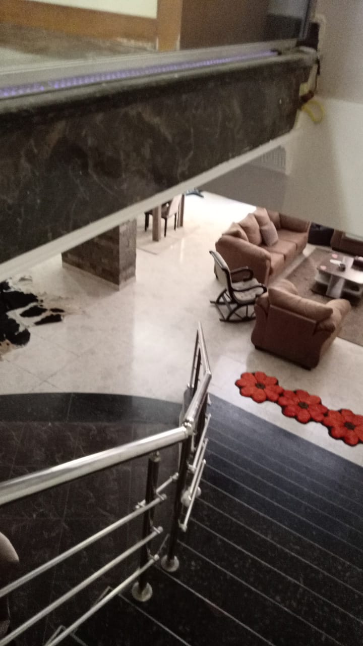 Stair railing overlooking a living area with red cushions - duplex in South of Academy, New Cairo