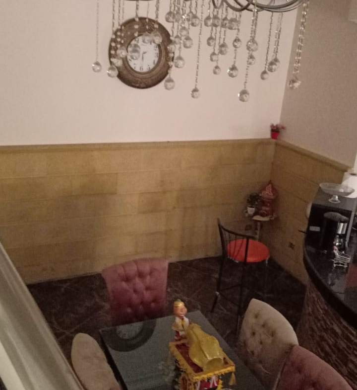 Living area with a crystal chandelier and a glass coffee table - duplex in South of Academy, New Cairo
