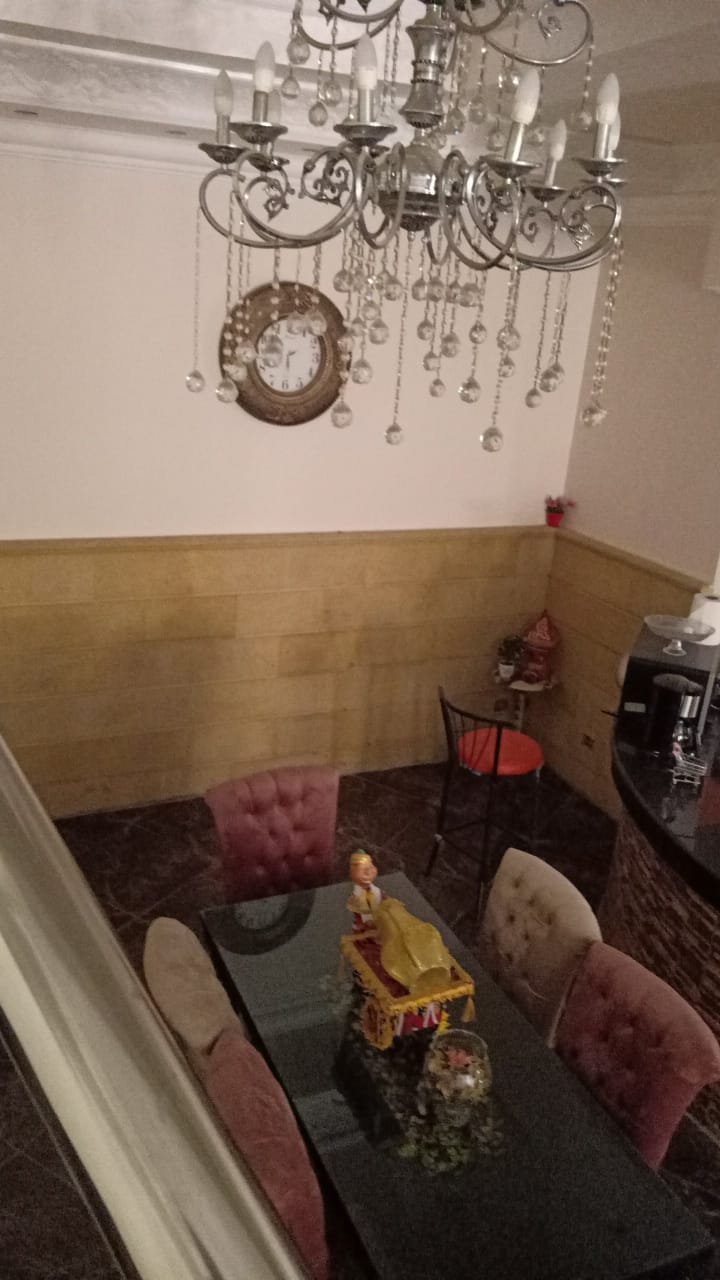 Living area with a crystal chandelier and a glass coffee table - duplex in South of Academy, New Cairo