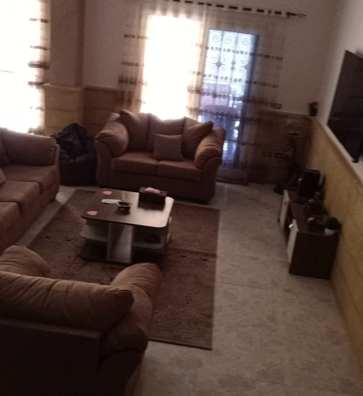 Living room with brown sofas and a sunlit window - duplex in South of Academy, New Cairo
