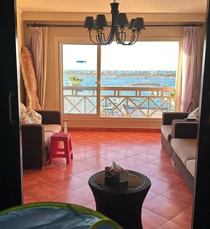 Living room with red flooring and chandelier - chalet in Porto Marina, El Alamein