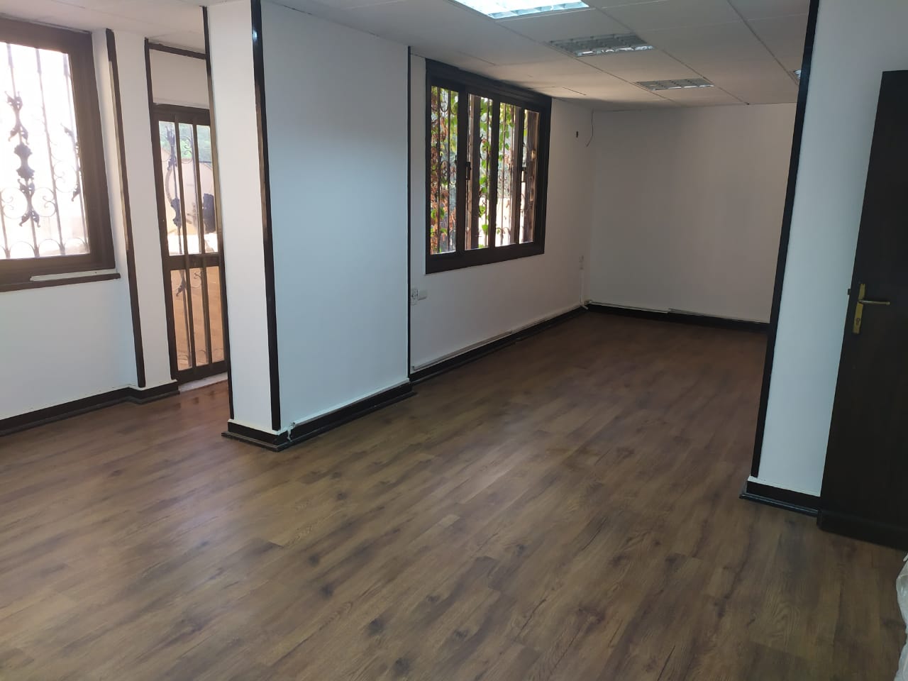 Empty room with several windows and wood floor - apartment in Zamalek