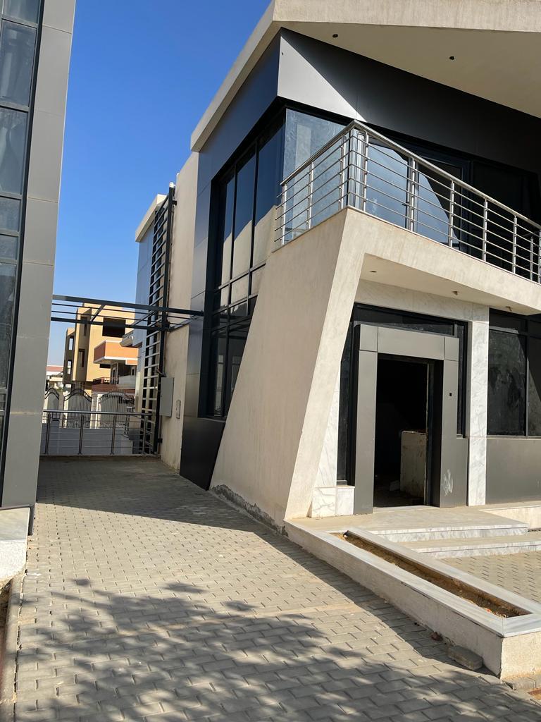 Side of a modern villa with a glass wall and a balcony - villa in Life View, New Cairo