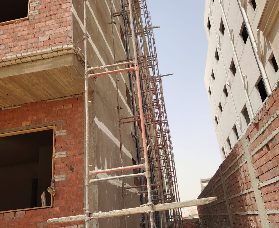 Brick facade of a building with scaffolding beside a neighbouring block - apartment in Bayt Al Watan, New Cairo
