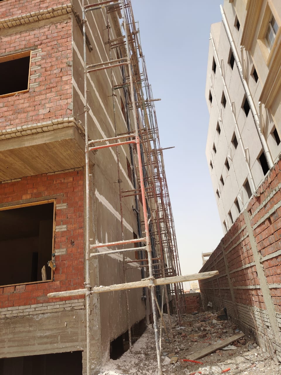 Brick facade of a building with scaffolding beside a neighbouring block - apartment in Bayt Al Watan, New Cairo