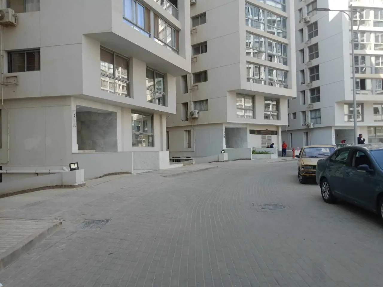 طريق فناء بين عمارات سكنية وسيارة واقفة - شقة في كمبوند ون قطامية، القاهرة الجديدة