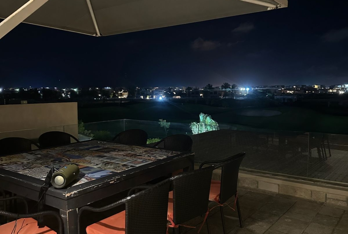 Outdoor dining table with orange chairs under a large parasol - chalet in Hacienda Bay, North Coast
