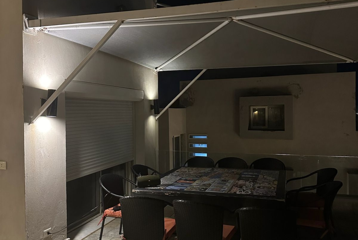 Dining set under a canopy on the roof at night - chalet in Hacienda Bay, North Coast