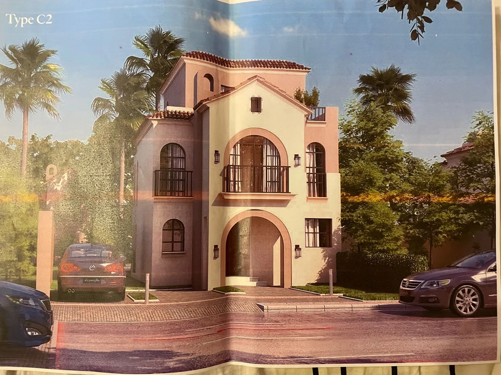 Brochure photo of a Mediterranean villa with an arched entrance and palms - villa in Sarai Cavana Lakes, Mostaqbal City