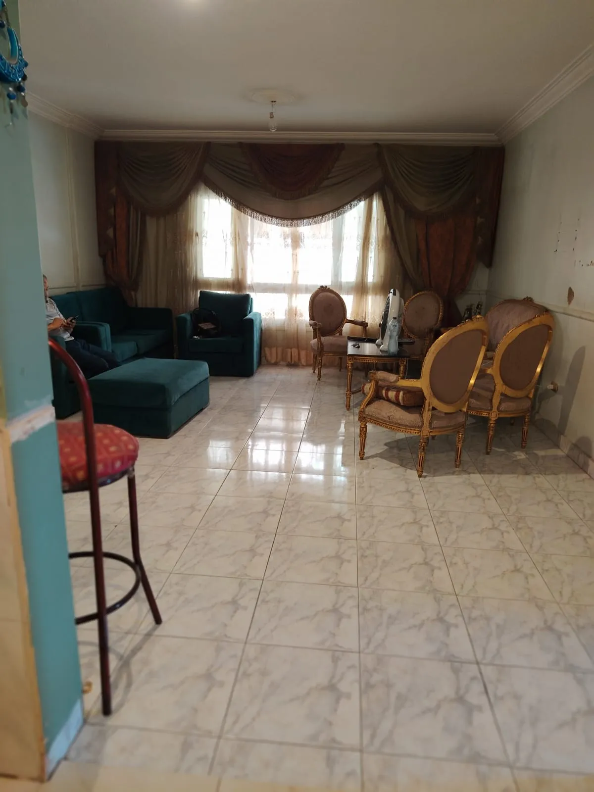 property-image-69fd35a31553e غرفة معيشة مع كراسي خوص ونوافذ واسعة - شقة في مساكن شيراتون، مصر الجديدة