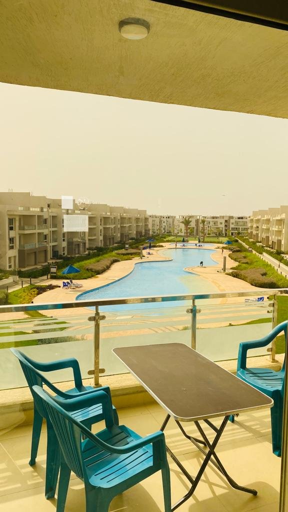 3-bedroom-chalet-for-sale-in-egypt-2 Balcony with table and chairs overlooking the pool at Aroma Resort